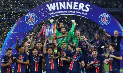 Skuad PSG mengangkat trofi Liga Champions 2025 di Allianz Arena, dikelilingi konfeti kemenangan.