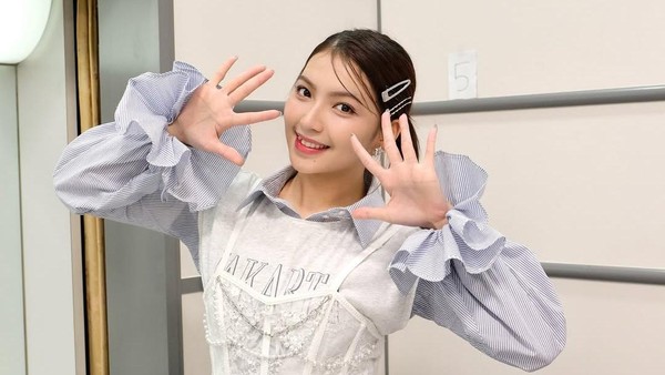 Emotif! Kelulusan Gracia JKT48 dan Babak Baru Kariernya 64 Gracia JKT48 tersenyum cerah sambil berpose tangan membentuk angka sepuluh di belakang panggung.